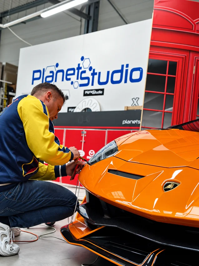 Wykończenie oklejenia przy przednim reflektorze w warsztacie Planet Studio.