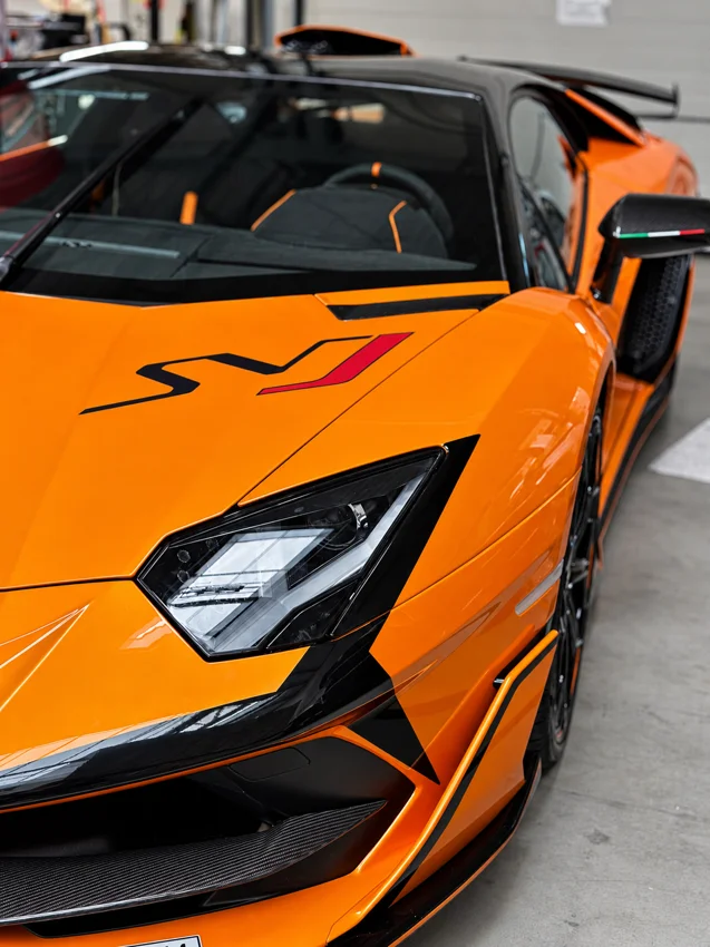 Pomarańczowa maska, reflektor i czarne elementy wykończenia Lamborghini.