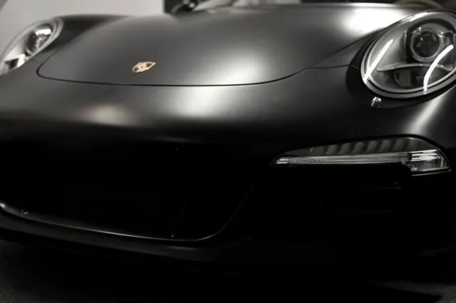 Zbliżenie czarnej, matowej maski i reflektora Porsche.